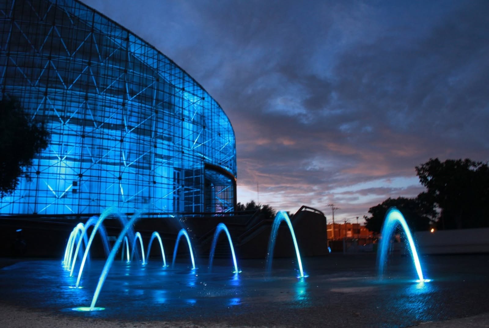 Fachada iluminada del Semilla Museo Interactivo durante el atardecer