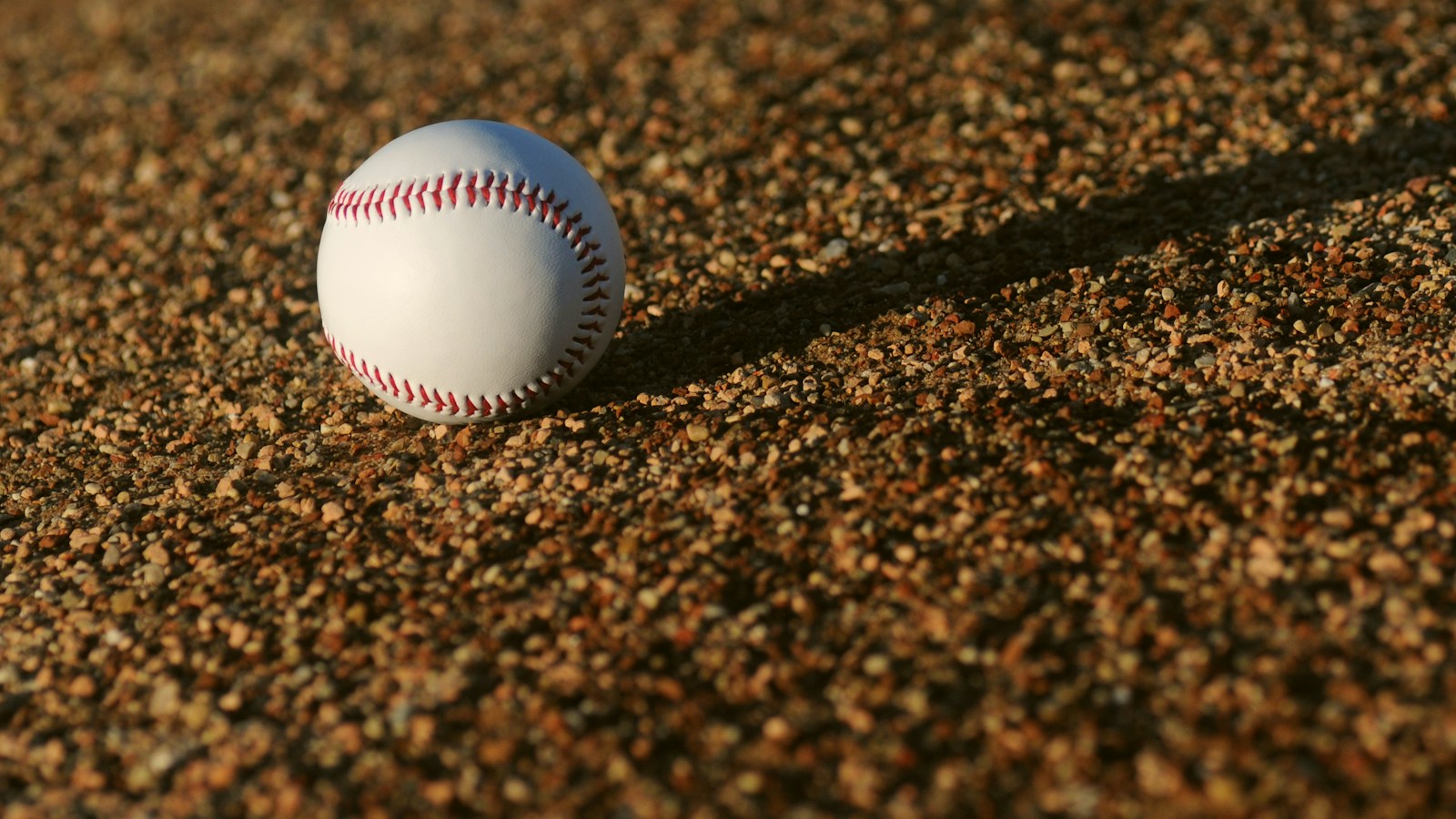 Pelota de béisbol sobre tierra; fotografía de archivo ilustrativa, no corresponde a los partidos reseñados